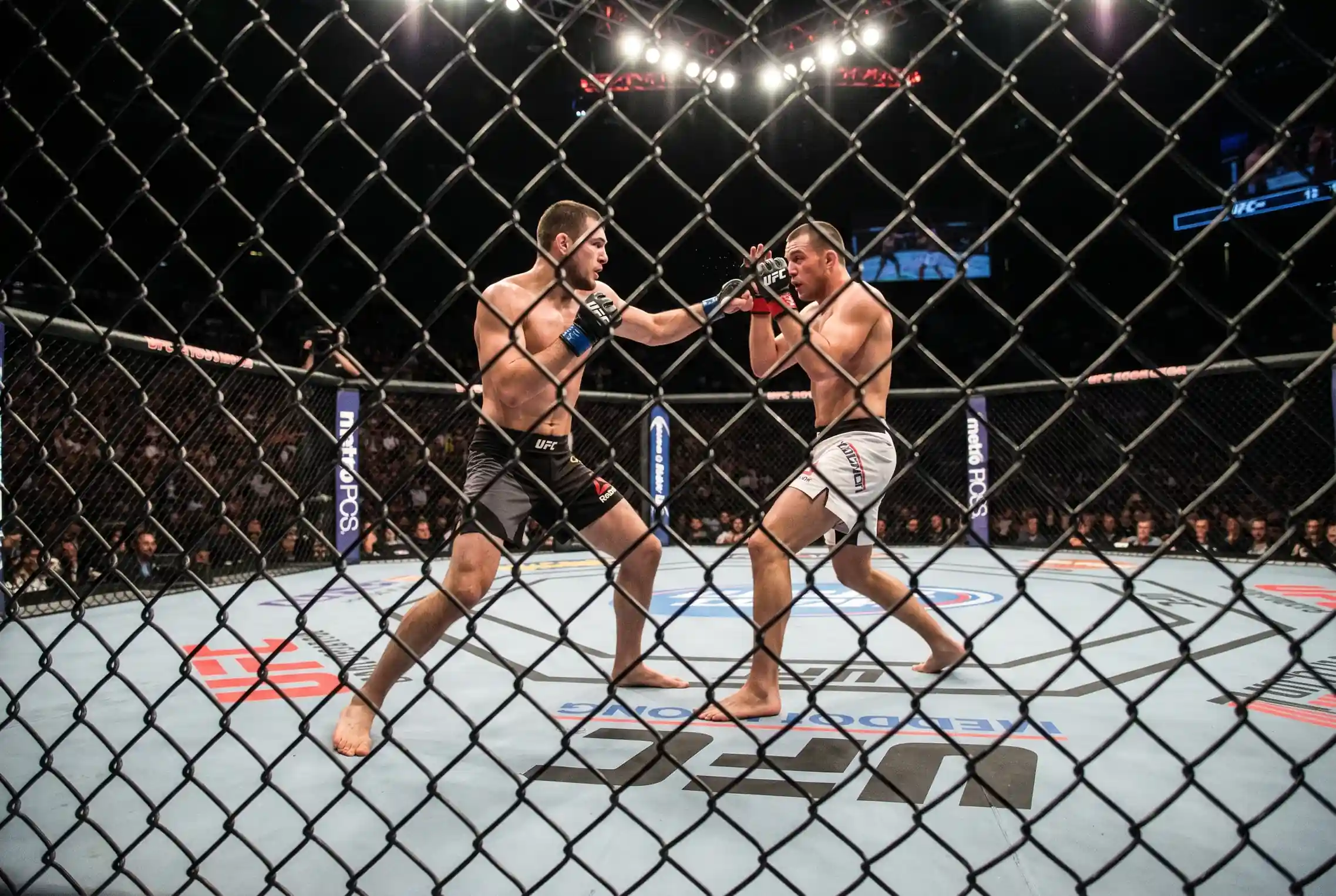 Zwei MMA-Kämpfer in unterschiedlichen Kampfpositionen im Octagon
